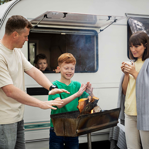 Famiglia con camper che si scalda vicino al fuoco